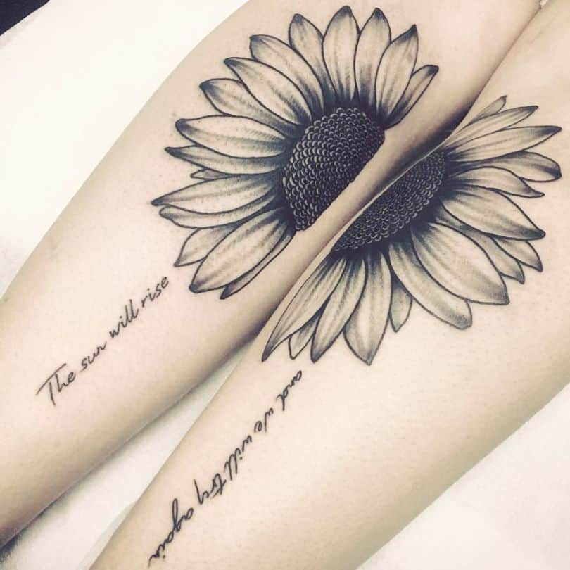 Matching sunflower tattoos on both thighs with bold shading and fine details, accompanied by cursive script reading 'The sun will rise' and 'and we will try again.'