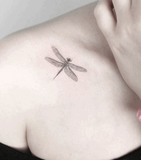 Delicate fine-line dragonfly tattoo on the upper shoulder, featuring intricate wing details for a minimalist and elegant look.