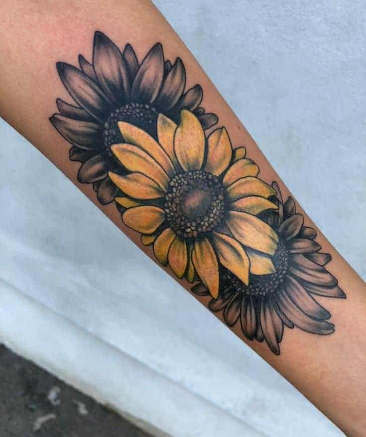 Forearm tattoo of three sunflowers, two in black and one in yellow