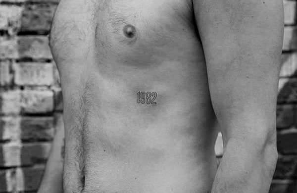 Man's torso with a "1992" tattoo on his side