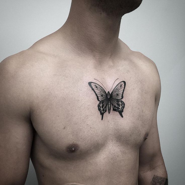 Bold black and grey butterfly tattoo on the chest with intricate shading, creating a striking and symbolic design.