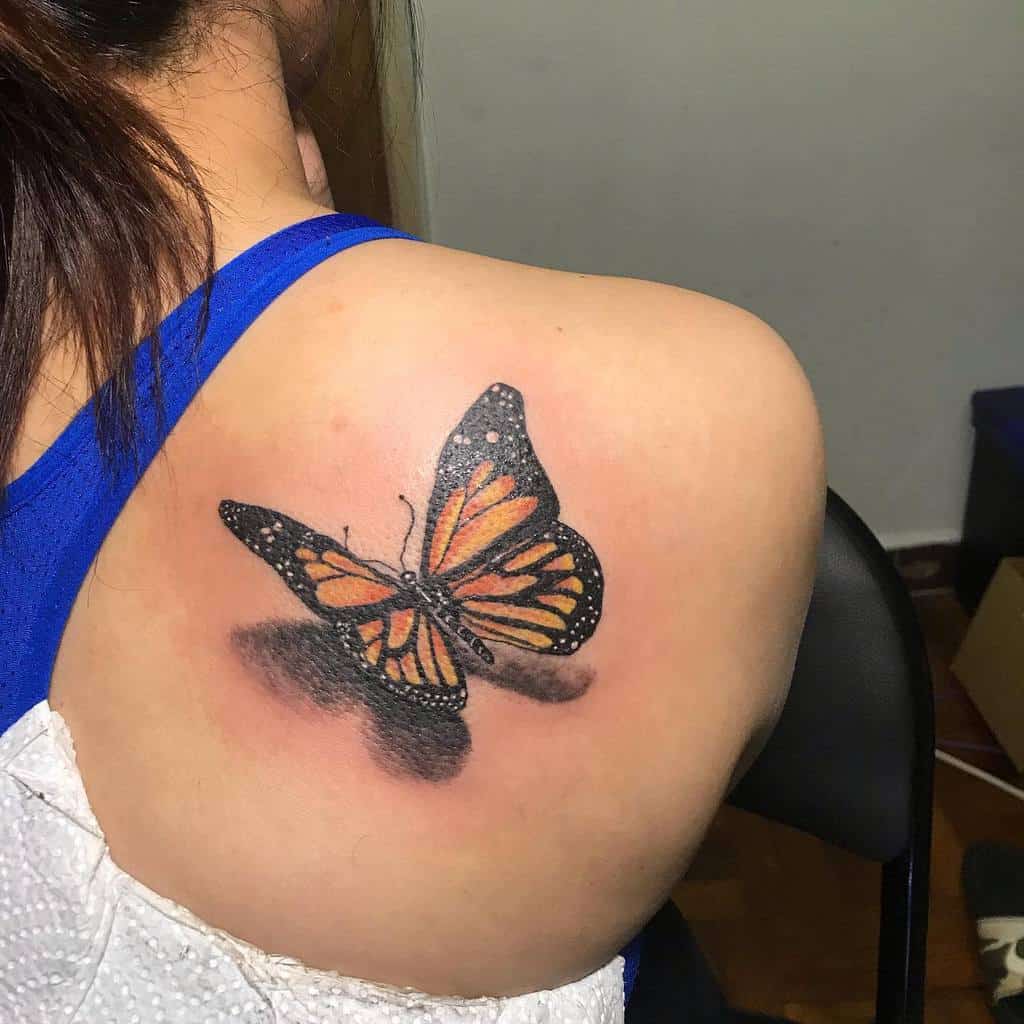 Realistic 3D butterfly tattoo with orange and black wings, positioned on the shoulder, creating a lifelike shadow effect