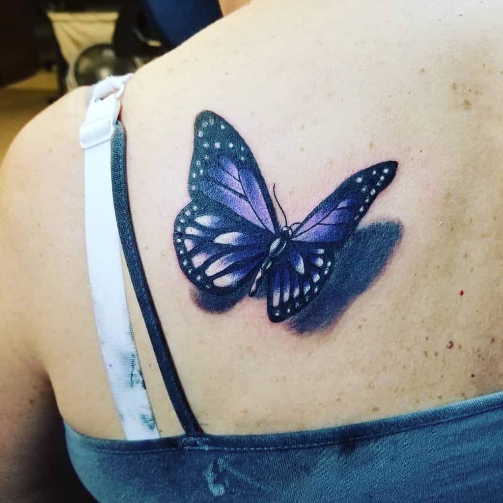 A purple butterfly tattoo on a woman's back, near the shoulder