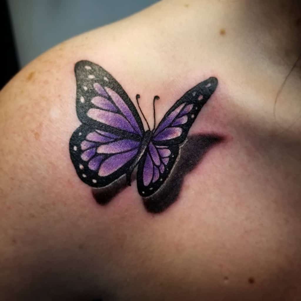 A purple and black butterfly tattoo on a shoulder