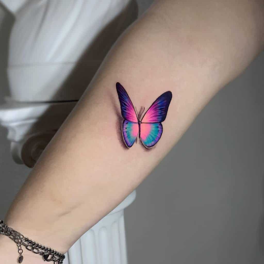 Tattoo of a colorful butterfly on a person's forearm, with blue, pink, and purple wings