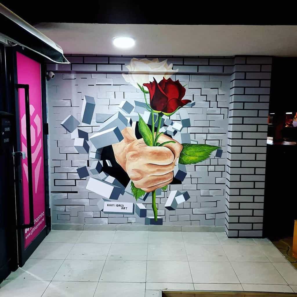 3d fist holding red rose breaking through bricks mural