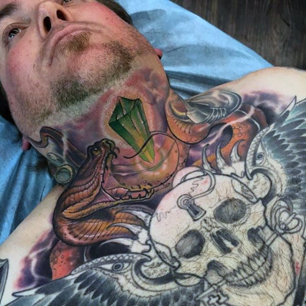 Throat tattoo featuring a 3D green gem, coiled serpents, and intricate skull design extending onto the chest with detailed shading
