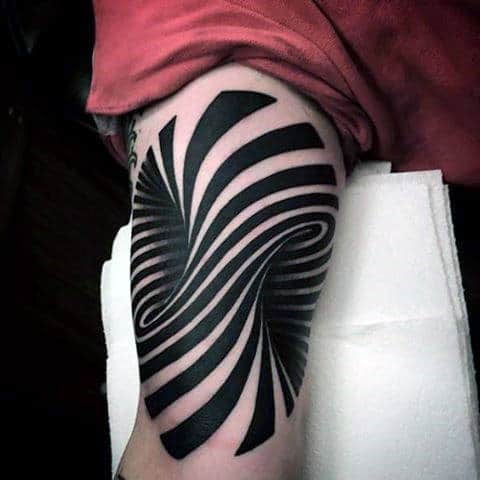 Black and white abstract tattoo with bold, swirling lines on a person's upper arm
