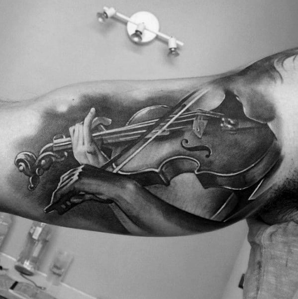 Realistic black and gray tattoo of a person playing the violin, placed on the inner arm with detailed shading and anatomical precision.