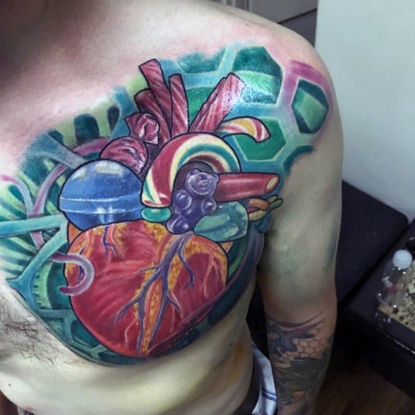 Colorful candy-themed tattoo of an anatomical heart blending realism and surrealism, featuring sweets and bold geometric patterns.