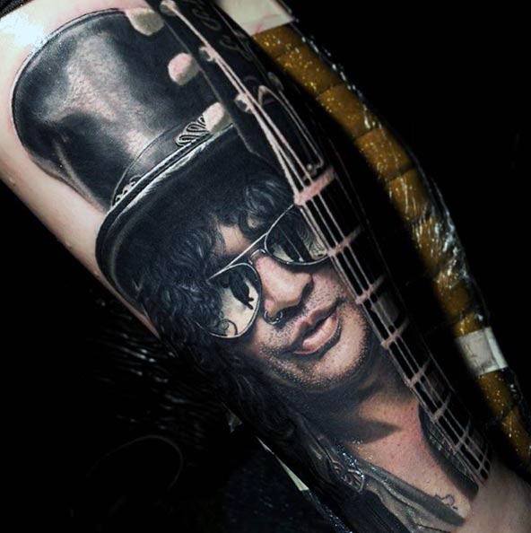 Hyper-realistic tattoo of Slash wearing sunglasses and a top hat, with a detailed guitar neck running across the design.
