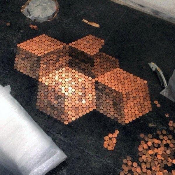 Penny tile floor with a 3D cube design in progress on a dark background.
