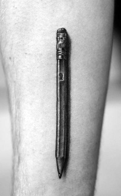 A striking, black and white tattoo captures the intricate details of a realistic pencil etched onto the skin