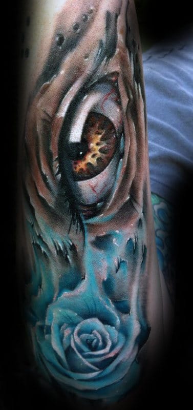 Realistic tattoo of a wolf eye with a blue rose below it