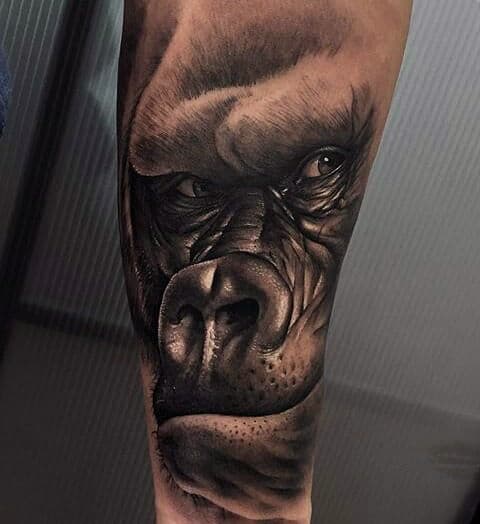 Realistic gorilla face tattoo on an arm, with intricate shading and lifelike details