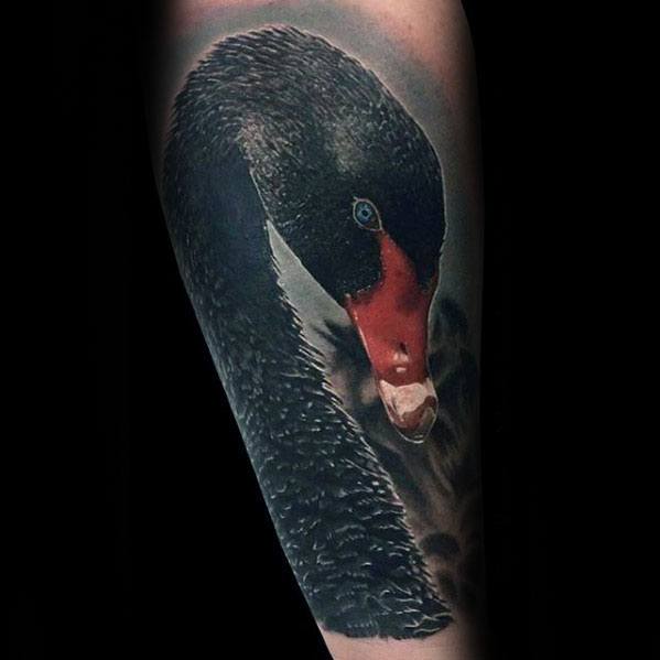 Realistic black swan tattoo with vivid red beak and piercing blue eye, showcasing elegance and mystery on a dark background.