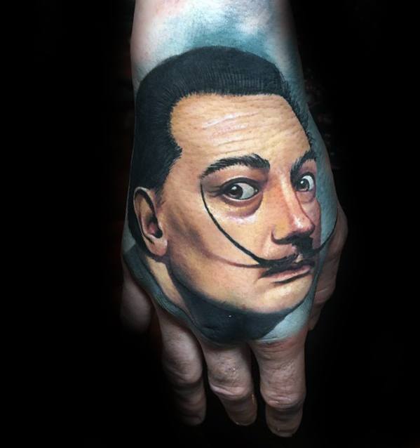 A vibrant hand tattoo depicting the iconic portrait of Salvador Dalí, highlighting his signature mustache