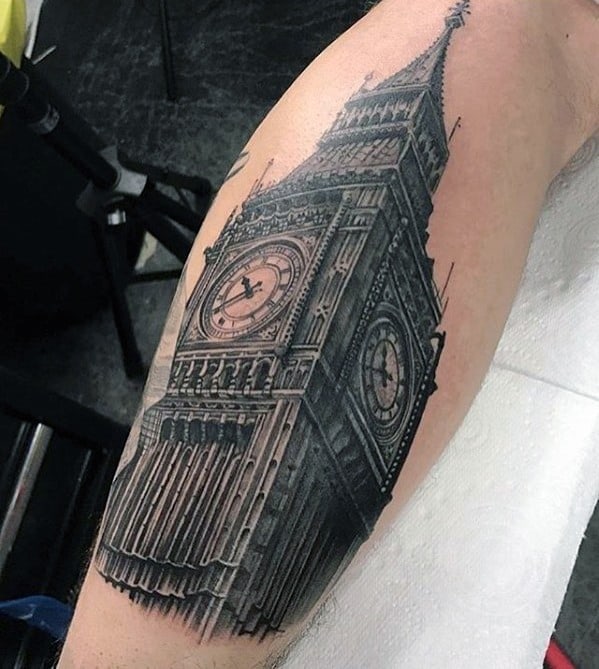Tattoo of Big Ben on a forearm with black and grey shading showing its intricate details