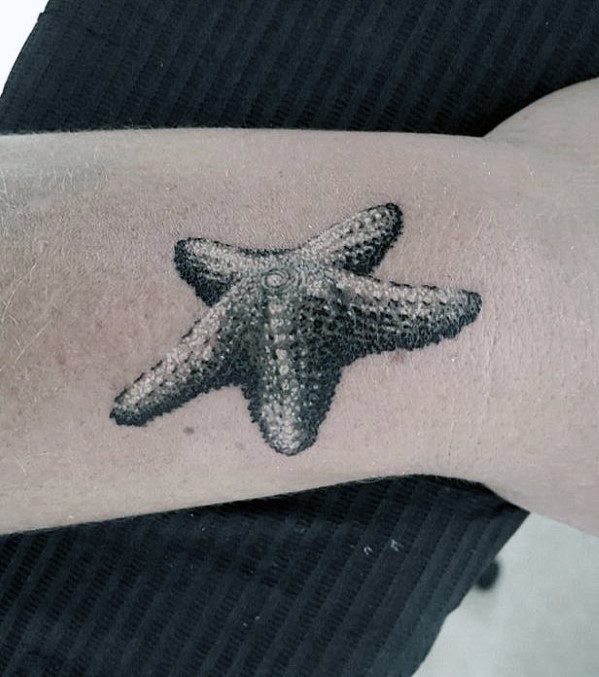 Realistic starfish tattoo on forearm with detailed texture and shading, giving a 3D effect against the skin.