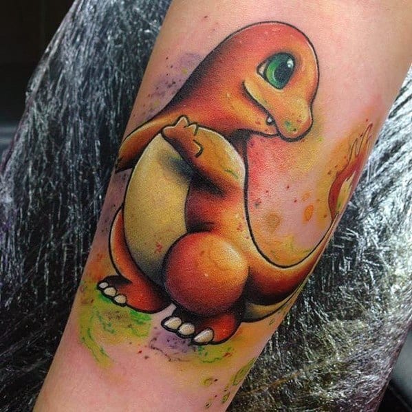 Colorful Charmander tattoo with a playful expression and fiery tail, inked on forearm with watercolor-style splashes.