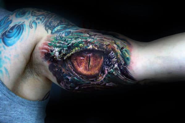 Detailed and colorful dragon eye tattoo on an upper arm