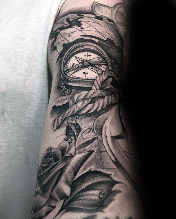 Tattoo of a compass, anchor, rope, and rose covering an arm detailed in black and gray ink