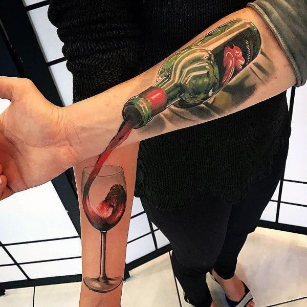 Realistic wine bottle tattoo on forearm, with red wine pouring into a glass tattoo on the inner arm, creating a 3D illusion.