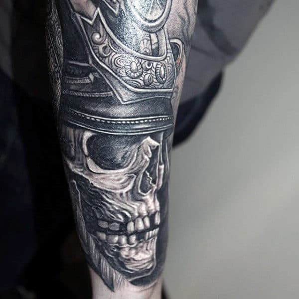 Detailed grayscale tattoo of a skull with armor on a person's forearm