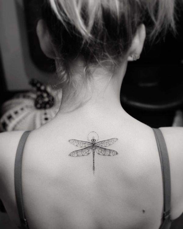 Delicate ornamental dragonfly tattoo on the upper back, featuring intricate fine-line details and symmetrical dot work for an elegant design.