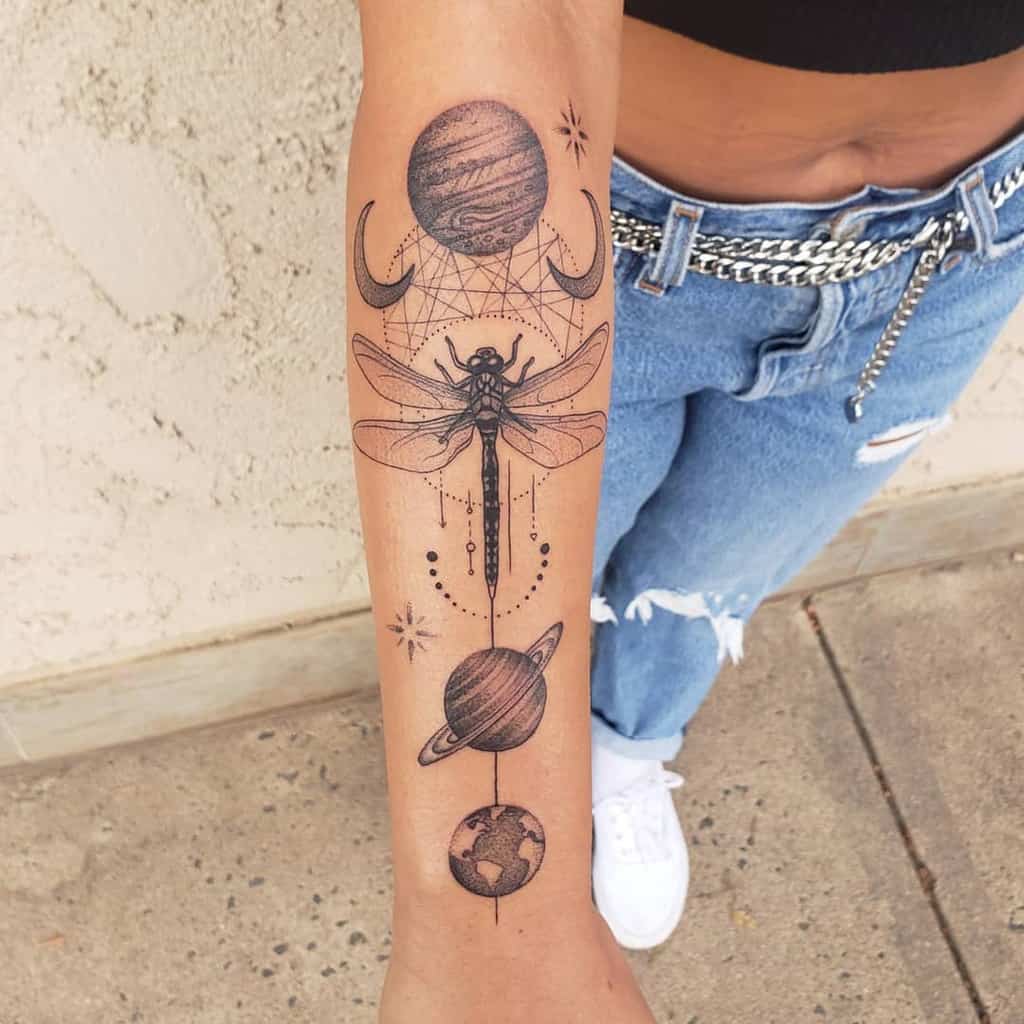 Intricate celestial dragonfly tattoo on the forearm, featuring planets, moons, geometric patterns, and fine dot work for a cosmic design.