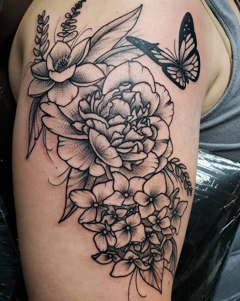 Intricate black and grey floral tattoo with a butterfly on the upper arm, featuring fine linework and detailed shading for an elegant look.