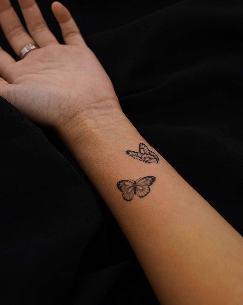 Delicate twin butterfly tattoos on the wrist, symbolizing transformation, freedom, and a graceful connection to nature.
