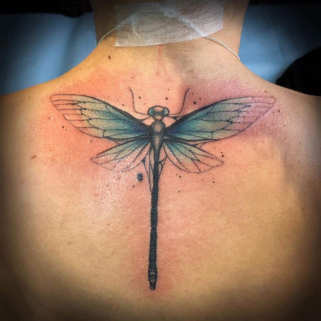 Large dragonfly tattoo on the upper back with delicate blue-green wings, fine line details, and subtle shading for a realistic effect.