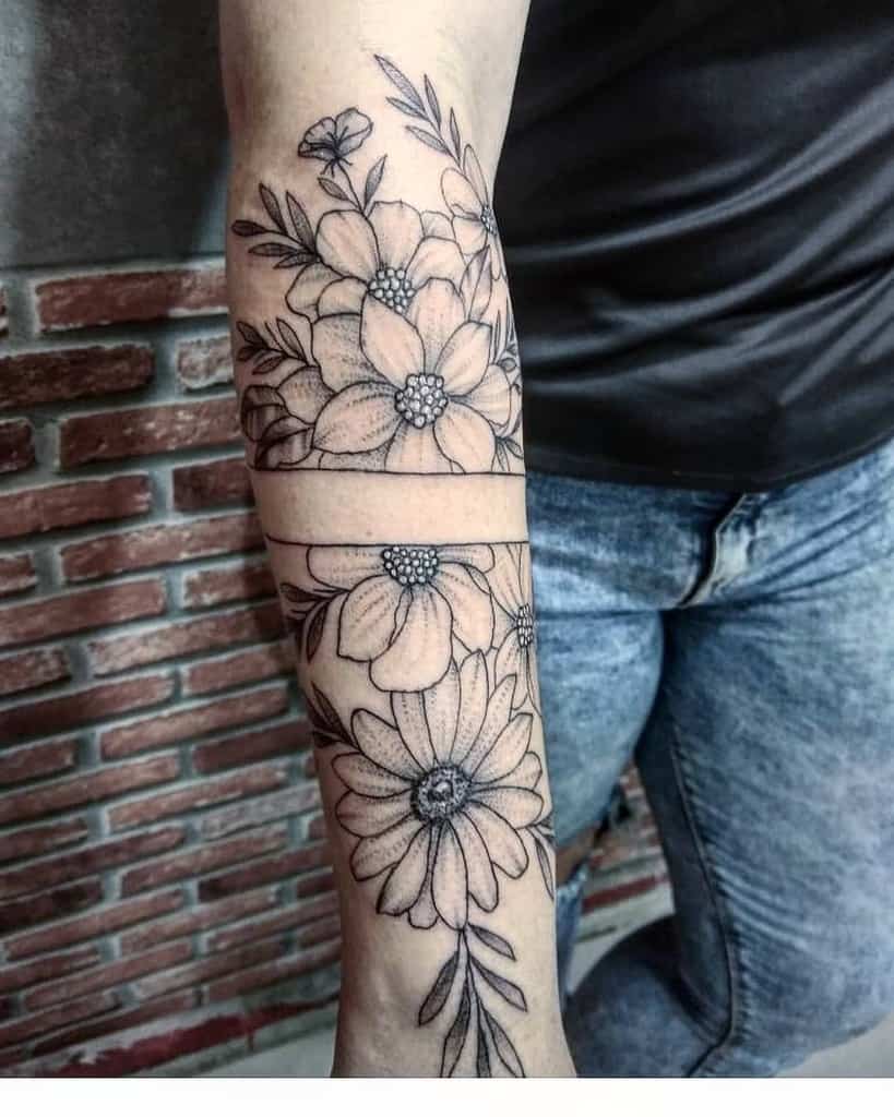 Black and grey forearm tattoo featuring a split design with detailed flowers, leaves, and a sunflower, creating a seamless wrap-around effect.
