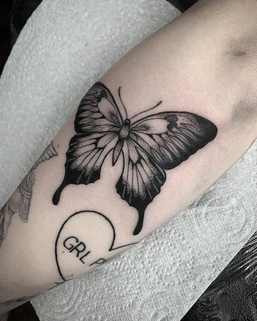 Bold black and grey butterfly tattoo with intricate shading, creating a striking and detailed design on the skin.