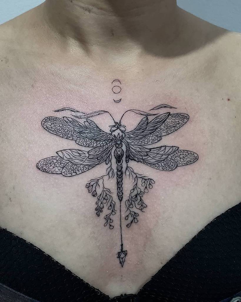 Intricate ornamental dragonfly tattoo on the chest, featuring fine-line details, botanical elements, and celestial symbols for a mystical look.
