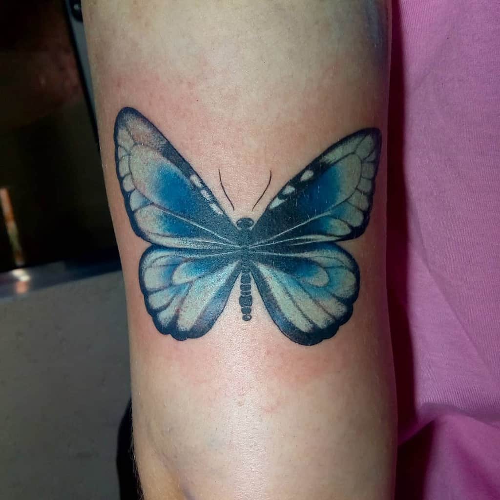 Vibrant blue butterfly tattoo on the arm with realistic shading and intricate details, creating a striking and elegant design.