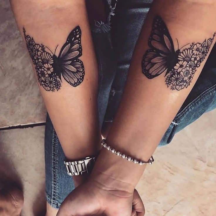 Matching black and grey butterfly tattoos on forearms with floral wing details, symbolizing growth, transformation, and connection.