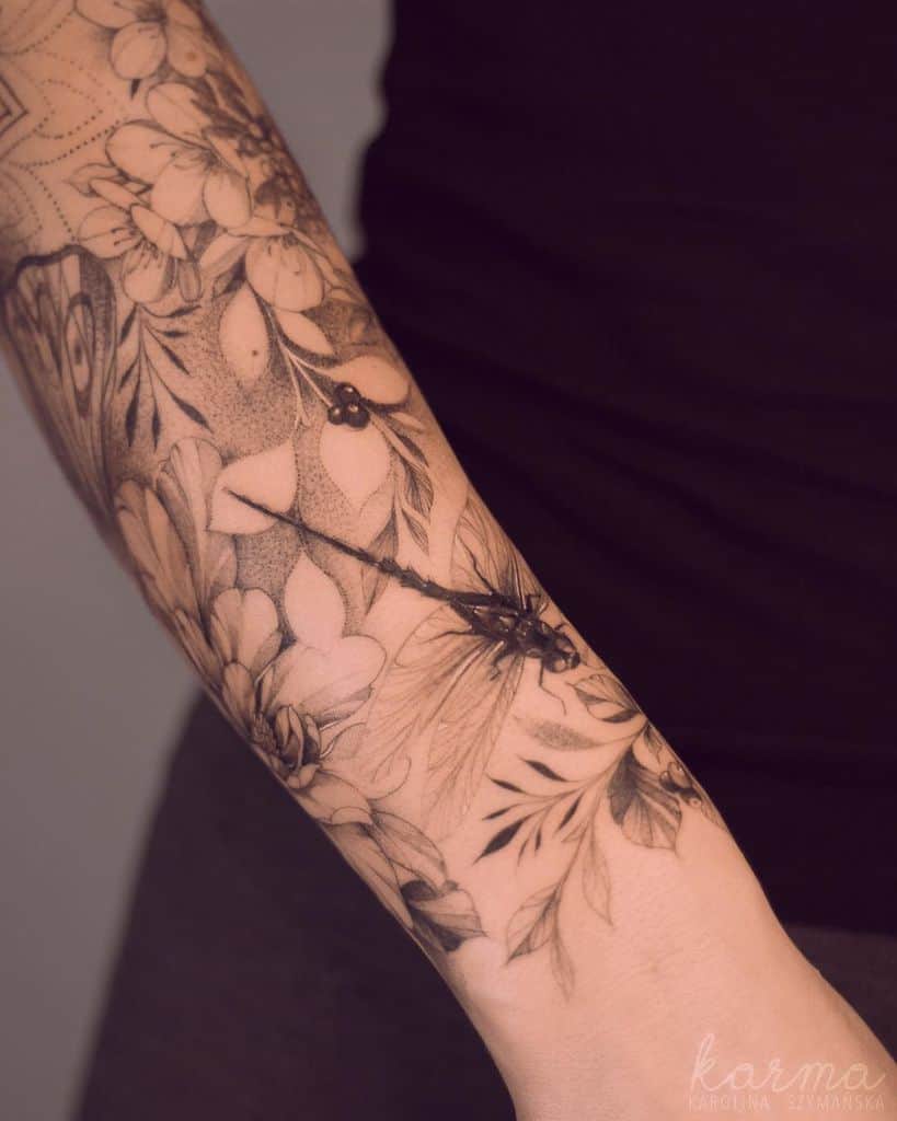 Intricate black and grey dragonfly tattoo sleeve with floral and botanical elements, featuring fine linework and soft dot shading.