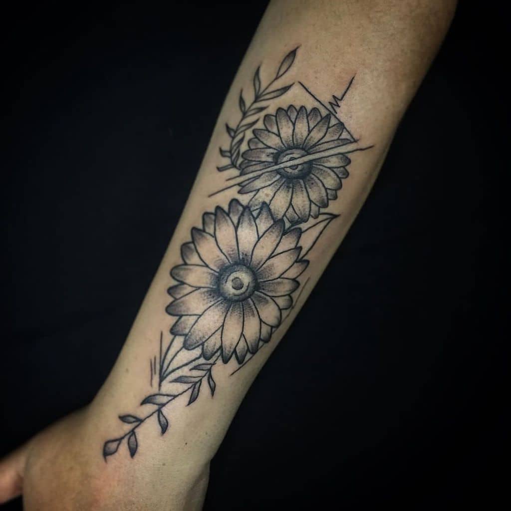 Black and grey forearm tattoo featuring two sunflowers with eye-like centers, geometric accents, and fine line leaves for a unique design.