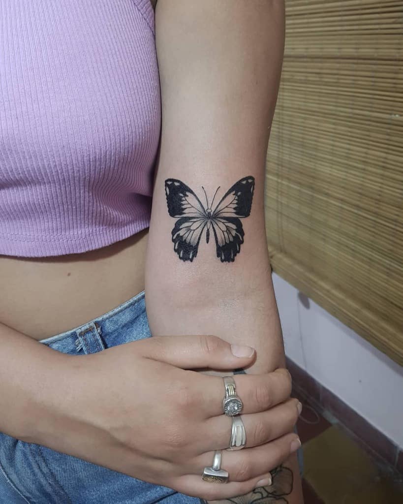 Bold black and grey butterfly tattoo on the forearm, featuring intricate shading for a striking and elegant look.