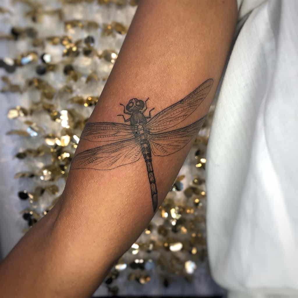 Realistic dragonfly tattoo on the forearm with intricate wing details and fine shading for a delicate, lifelike effect.
