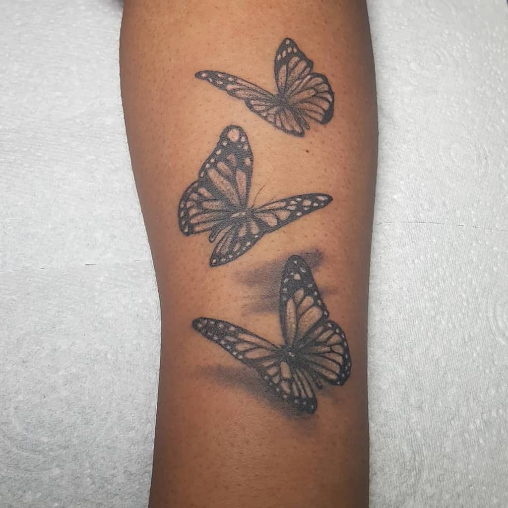 Elegant black and grey butterfly tattoo with a soft 3D shadow effect, creating a realistic and graceful flight illusion on the skin.