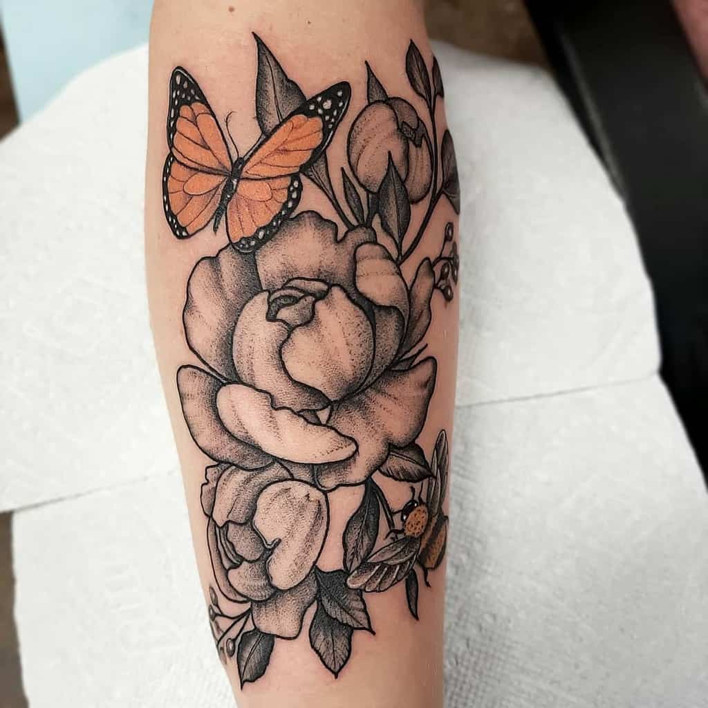 Elegant floral tattoo with a vibrant orange butterfly, combining black and grey shading with a pop of color for a striking forearm design.