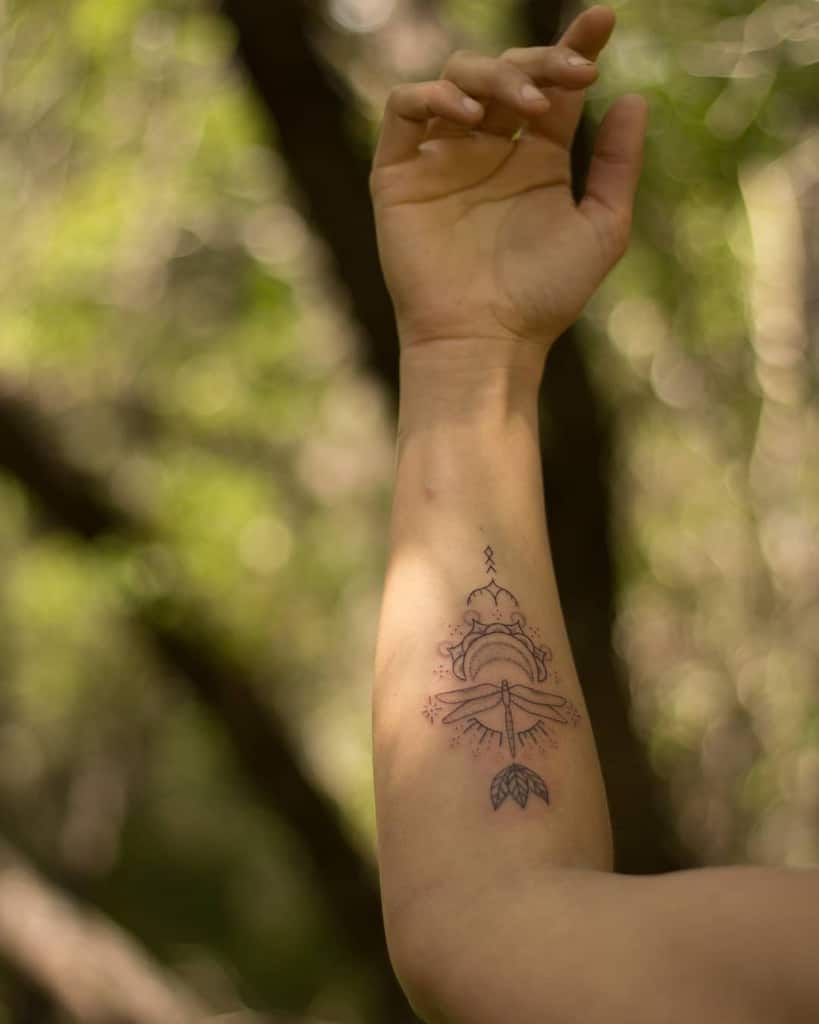 Delicate dragonfly tattoo on the forearm, featuring fine linework, ornamental details, and a minimalist nature-inspired design.