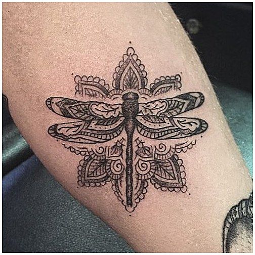 Mandala-style dragonfly tattoo featuring intricate patterns, bold black ink, and ornamental details for a decorative look.