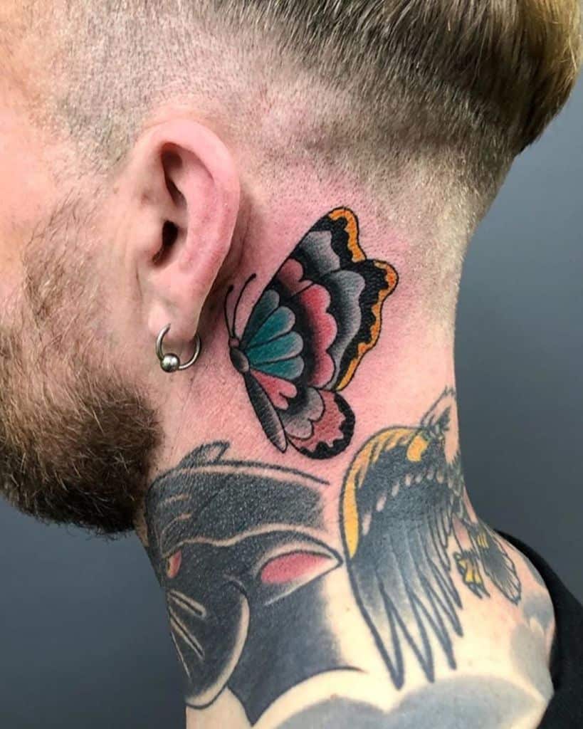 Colorful butterfly tattoo on the side of the neck, featuring bold black outlines with vibrant teal, pink, and orange shading in a traditional style.