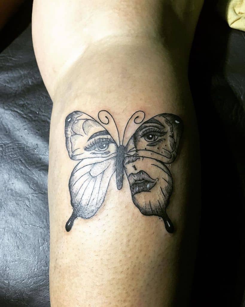 Unique black and grey butterfly tattoo with a surreal face design, blending realism and artistic creativity.