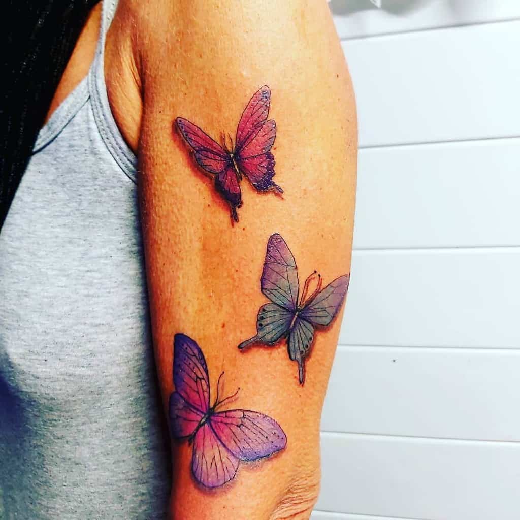 Beautiful watercolor-style butterfly tattoo with shades of pink and purple, giving a delicate and artistic touch to the arm.