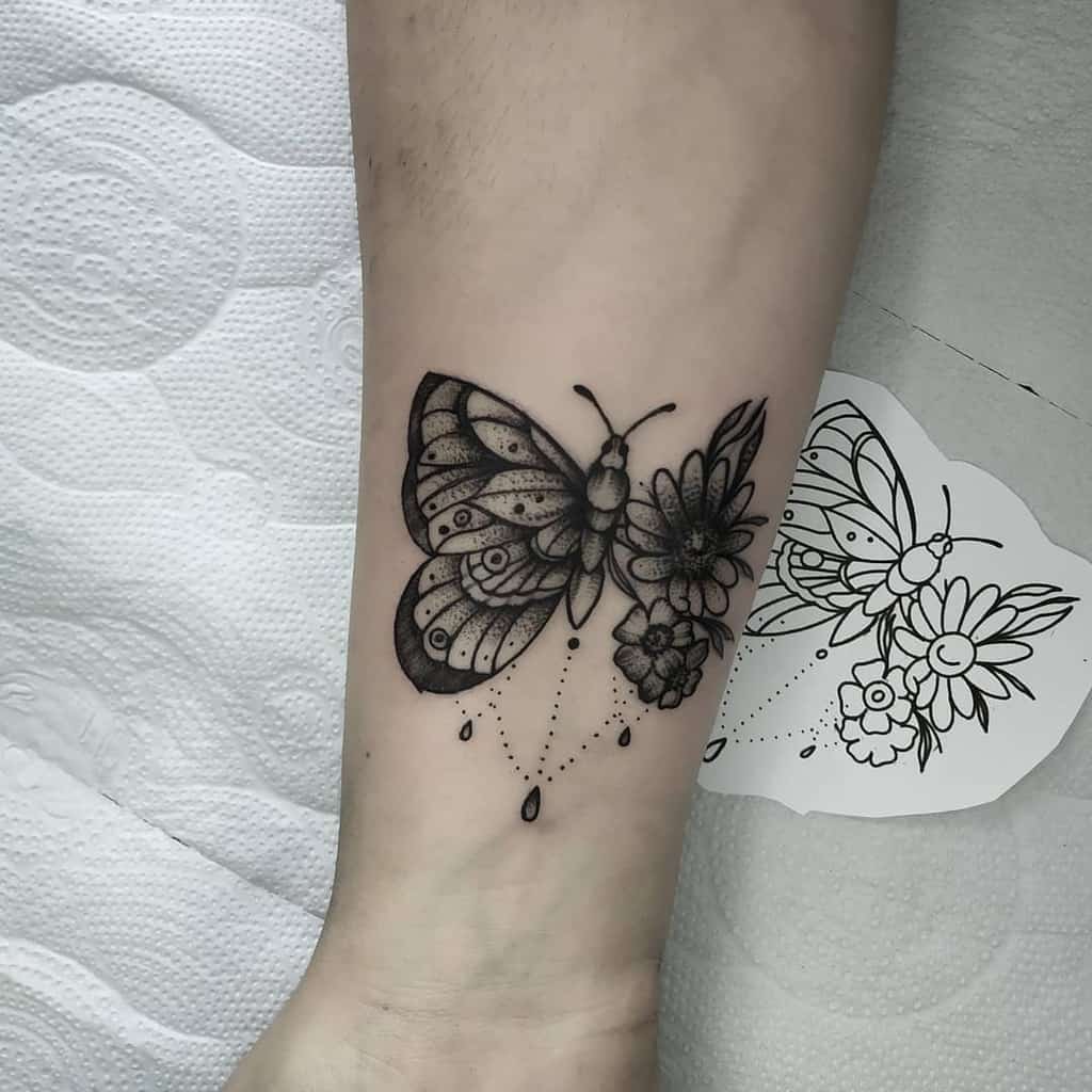 Elegant black and grey butterfly tattoo with floral wing details and ornamental dots, symbolizing transformation and beauty.